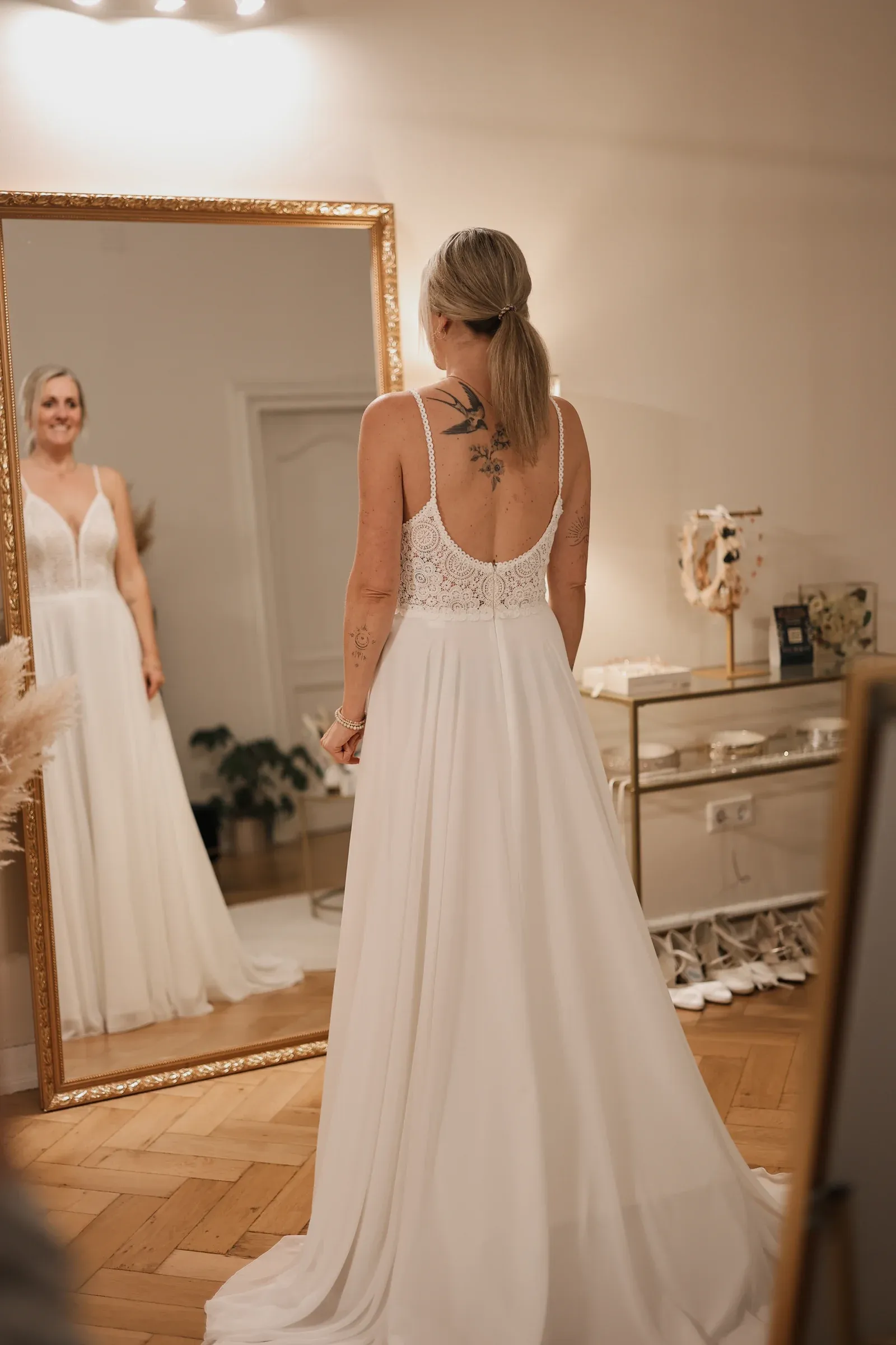 Braut betrachtet ihr Kleid im großen Spiegel der Boutique