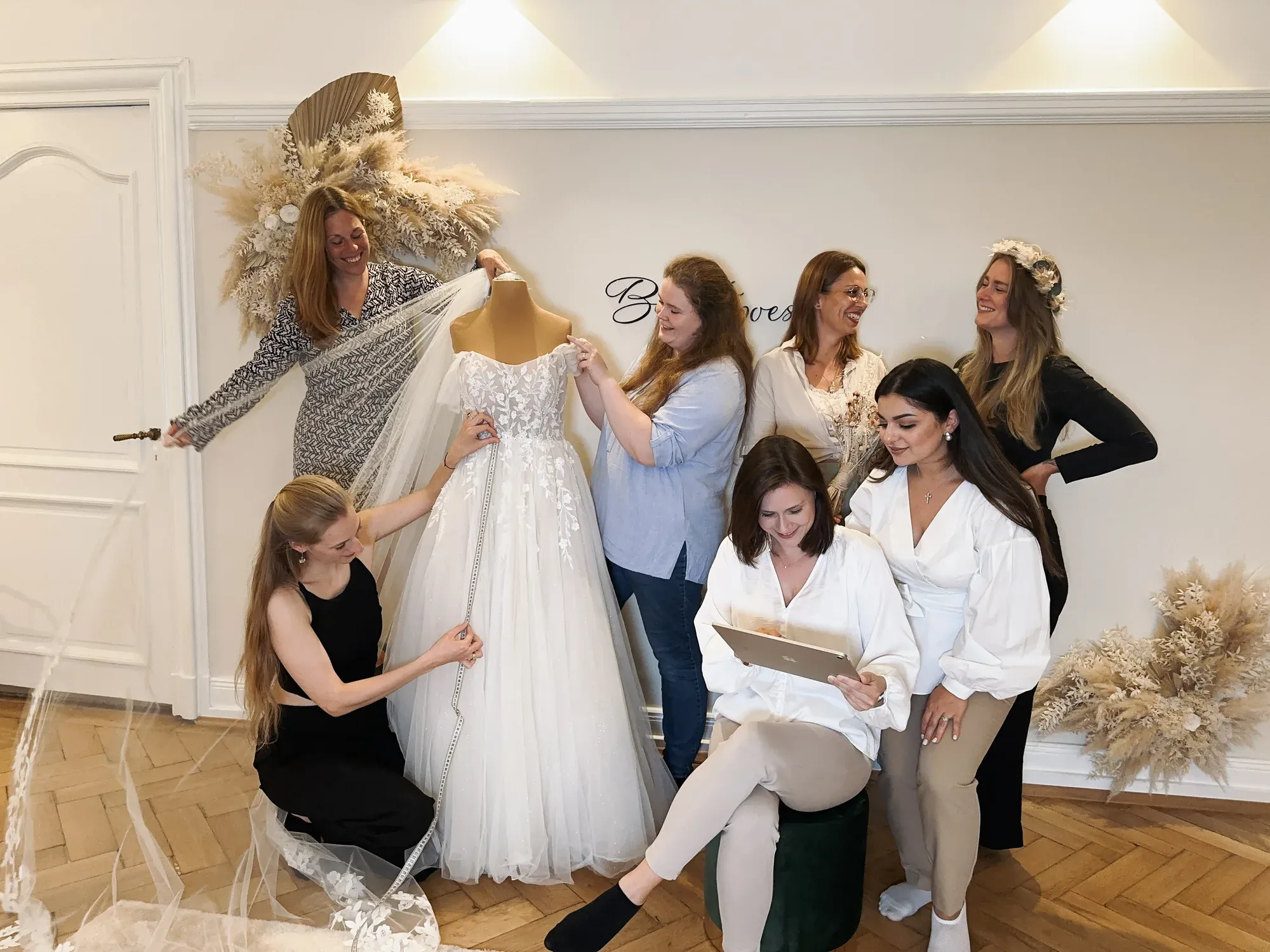 Das Brautpoesie-Team arbeitet gemeinsam an einem Brautkleid